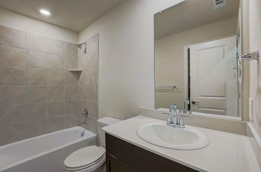 Full bathroom featuring vanity, tiled shower / bath, and toilet