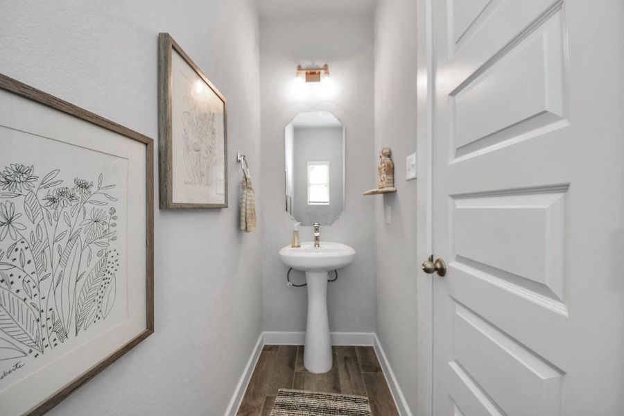 This half bathroom features a stylish pedestal sink, modern hardware, vanity lights and bright recessed lighting, creating a sleek and inviting space. This half bathroom features a stylish pedestal sink, modern hardware, vanity lights and bright recessed lighting, creating a sleek and inviting space.