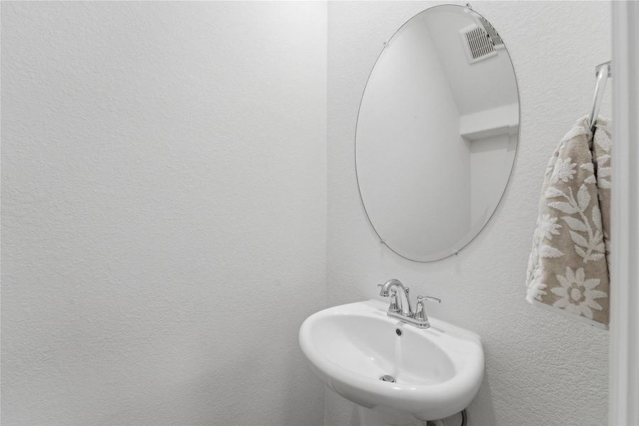 A pristine pedestal sink paired with a sleek oval mirror creates a minimalist powder room. A pristine pedestal sink paired with a sleek oval mirror creates a minimalist powder room.