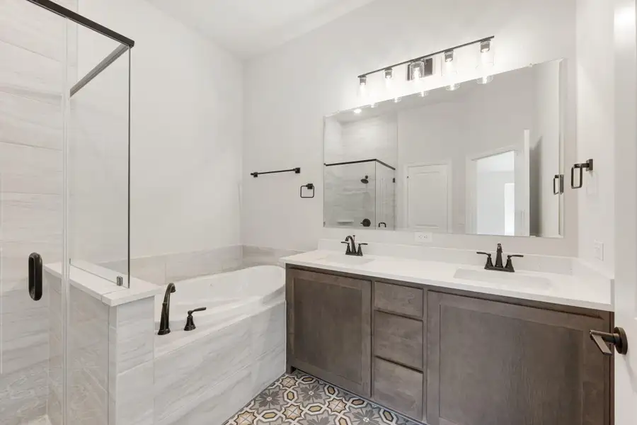 Master bathroom with double vanity, soaking tub, glass shower, and patterned tile floor Master bathroom with double vanity, soaking tub, glass shower, and patterned tile floor