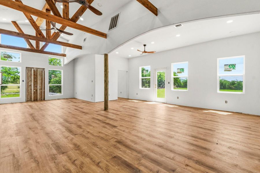 Breathtaking wood-beamed vaulted ceilings paired with custom ceiling fans create an immediate wow factor upon entry, showcasing the home’s character, craftsmanship & inviting open feel.