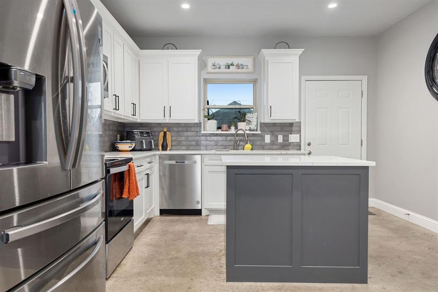 Kitchen with sink, white cabinetry, tasteful backsplash, a kitchen island, and stainless steel appliances