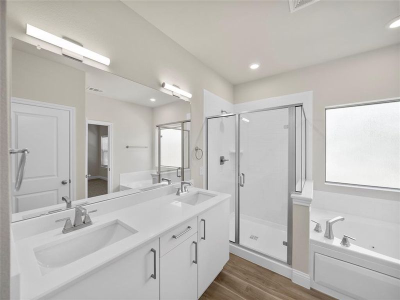 Full bathroom featuring a sink, a shower stall, a bath, and wood finished floors