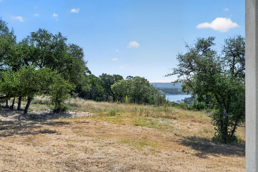 Mature trees frame a peaceful distant water view from the gently sloping property.