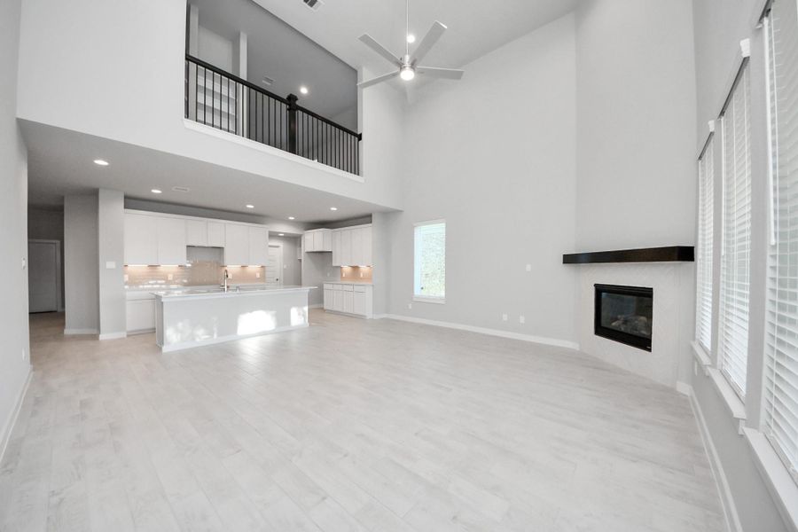 Welcome family and guests to your charming living room! With its high ceilings, recessed lighting, ceiling fan, custom paint, beautiful flooring, and large windows that let in abundant natural light, this room is perfect for gatherings. Sample photo of completed home with similar floor plan. Actual colors and selections may vary.