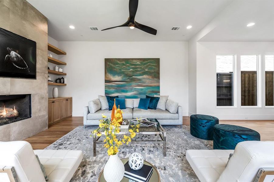 Living room with a premium fireplace, wood-type flooring, and ceiling fan