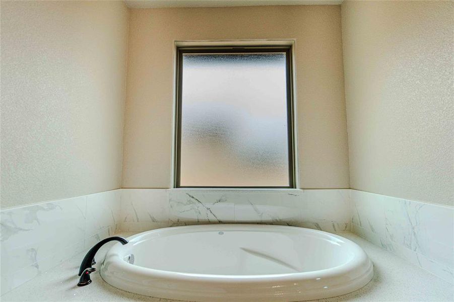 Bathroom featuring a wealth of natural light and a tub to relax in