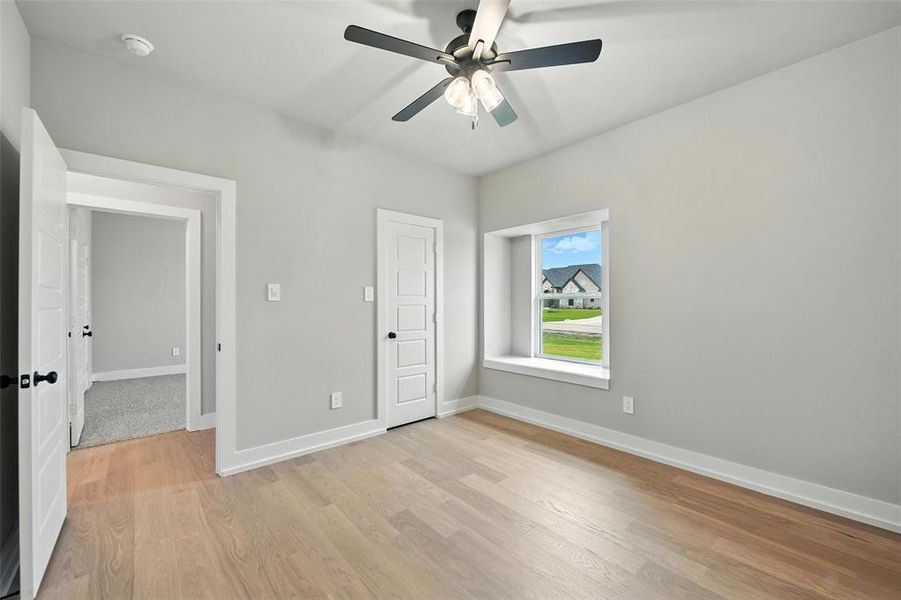 Unfurnished bedroom with light wood-type flooring and a ceiling fan Unfurnished bedroom with light wood-type flooring and a ceiling fan