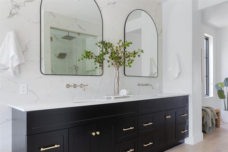 Bathroom featuring a healthy amount of sunlight, dual vanity, backsplash, and hardwood / wood-style floors