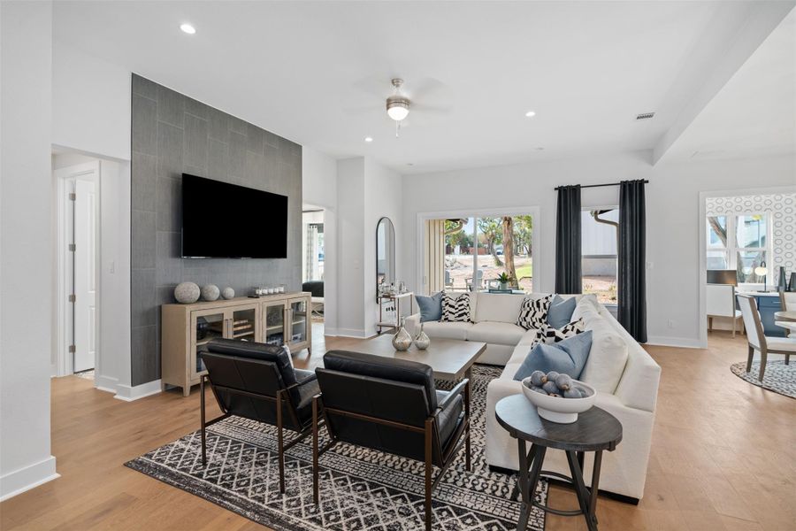Living room with a ceiling fan, light wood-style floors, and recessed lighting. The photos shown are of a completed home with the same floor plan and may not reflect the exact finishes, features, or layout of the home currently under construction.