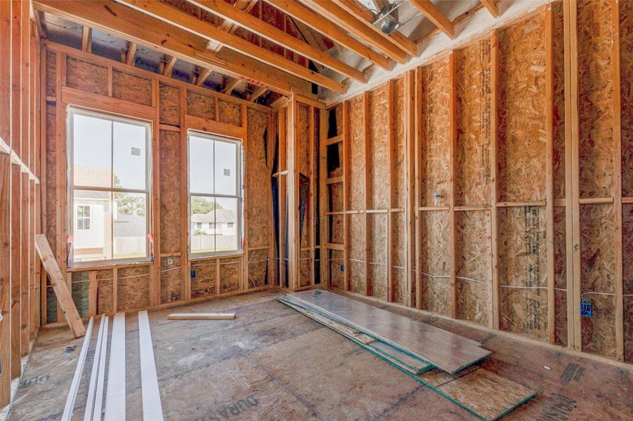 Framed room with two large windows bringing in natural light and views of the surrounding community. The exposed wood framing, ceiling structure, and construction materials help buyers visualize the finished space as a future bedroom, guest room, office, or flexible retreat within the home’s private upper level. Framed room with two large windows bringing in natural light and views of the surrounding community. The exposed wood framing, ceiling structure, and construction materials help buyers visualize the finished space as a future bedroom, guest room, office, or flexible retreat within the home’s private upper level.