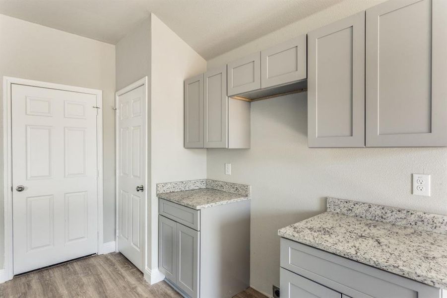 Kitchen with gray cabinetry, light wood-type flooring, and light stone countertops