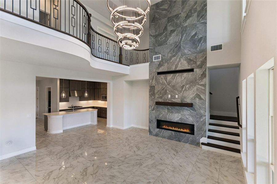 A grand, open-concept living area features a modern linear fireplace, a gourmet kitchen, and an elegant second-story balcony overlooking all.