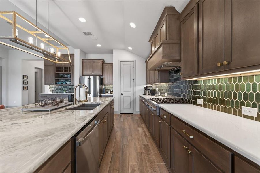 Kitchen with dark wood finished floors, stainless steel appliances, light stone counters, tasteful backsplash, and dark wood finish cabinetry Kitchen with dark wood finished floors, stainless steel appliances, light stone counters, tasteful backsplash, and dark wood finish cabinetry