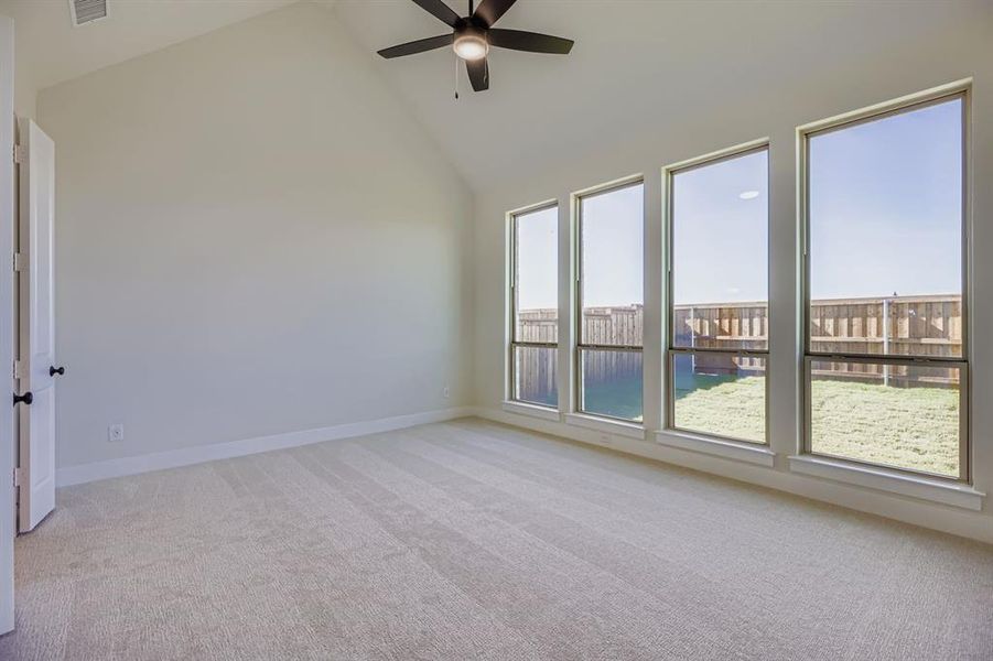 Spare room with high vaulted ceiling, light colored carpet, and ceiling fan Spare room with high vaulted ceiling, light colored carpet, and ceiling fan