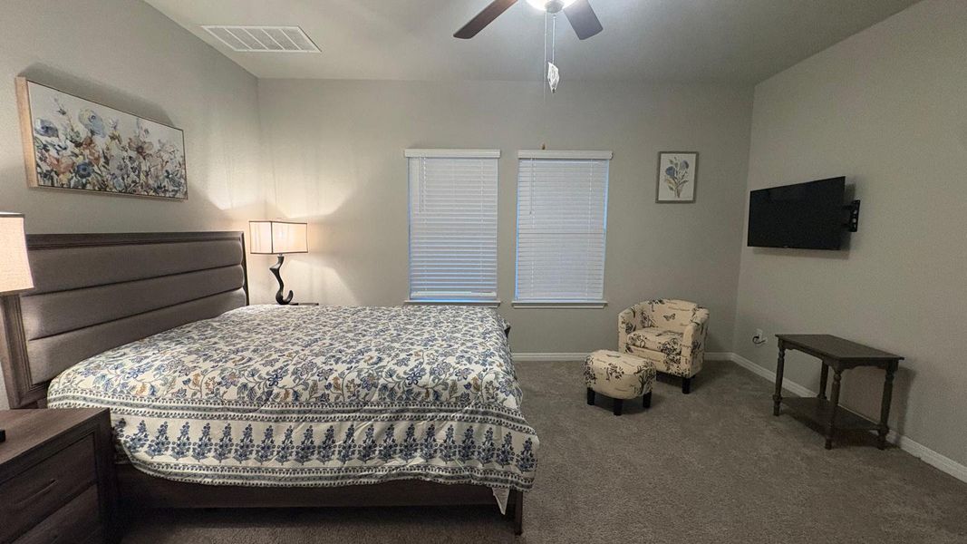 Rest peacefully in this primary bedroom featuring soft carpeting and natural light from the windows.