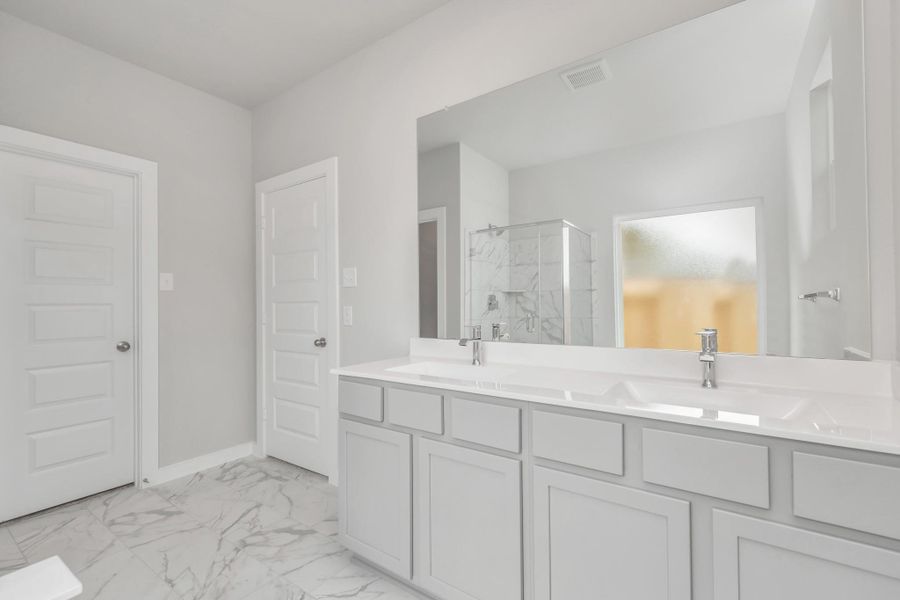 Elevate your daily routine at the elegant vanity, now equipped with double sinks, light countertops, modern hardware, and beautiful recessed lights. Sample photo of completed home with similar floor plan. Actual colors and selections may vary.