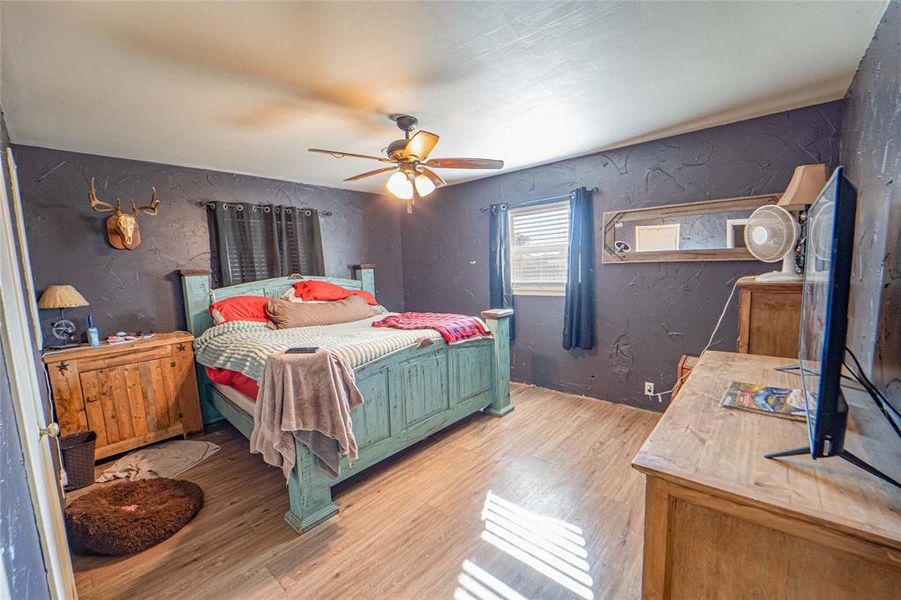 Bedroom featuring a textured wall, light wood-type flooring, and ceiling fan