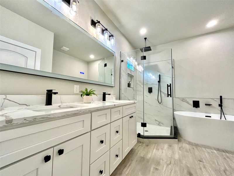 Primary bathroom with soak in tub, large lighted mirror with different features, and walk in shower.