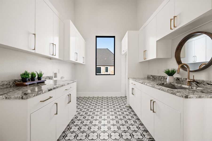 Laundry Room featuring light stone countertops, sink, and white cabinets