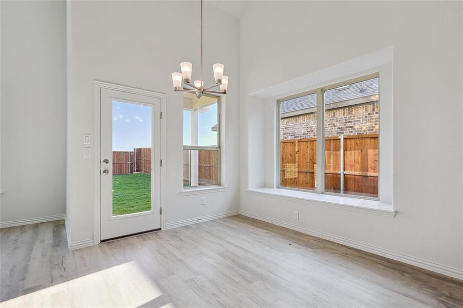 Unfurnished dining area featuring light hardwood / wood-style flooring, a towering ceiling, and plenty of natural light