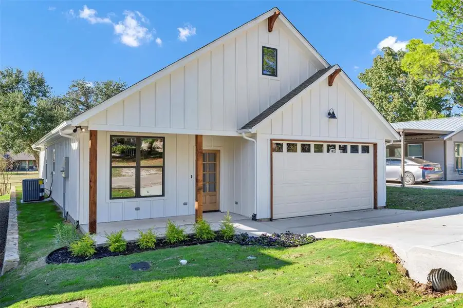 Modern farmhouse featuring board and batten siding, a garage, a front yard, and concrete driveway