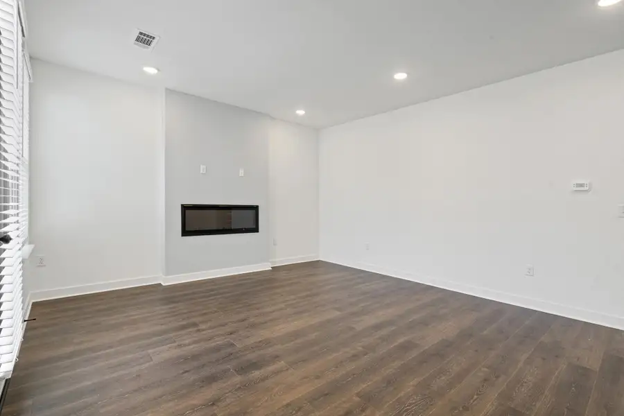 Contemporary living area featuring a built-in linear fireplace, wood-finish flooring, recessed lighting, and white window blinds