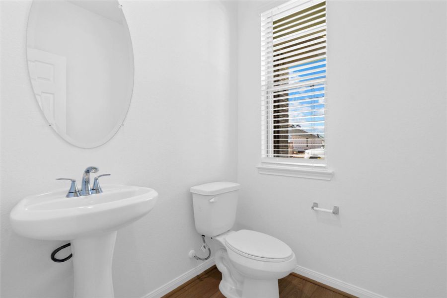 Guests will appreciate this stylish half bath, featuring a pedestal sink, oval mirror, and stylish fixtures adding polished convenience to the main level. Guests will appreciate this stylish half bath, featuring a pedestal sink, oval mirror, and stylish fixtures adding polished convenience to the main level.