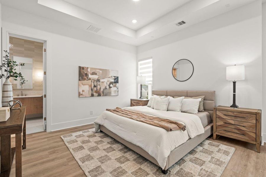 The primary suite balances scale and simplicity, where a tray ceiling introduces architectural depth and dimension while maintaining an atmosphere of quiet refinement.