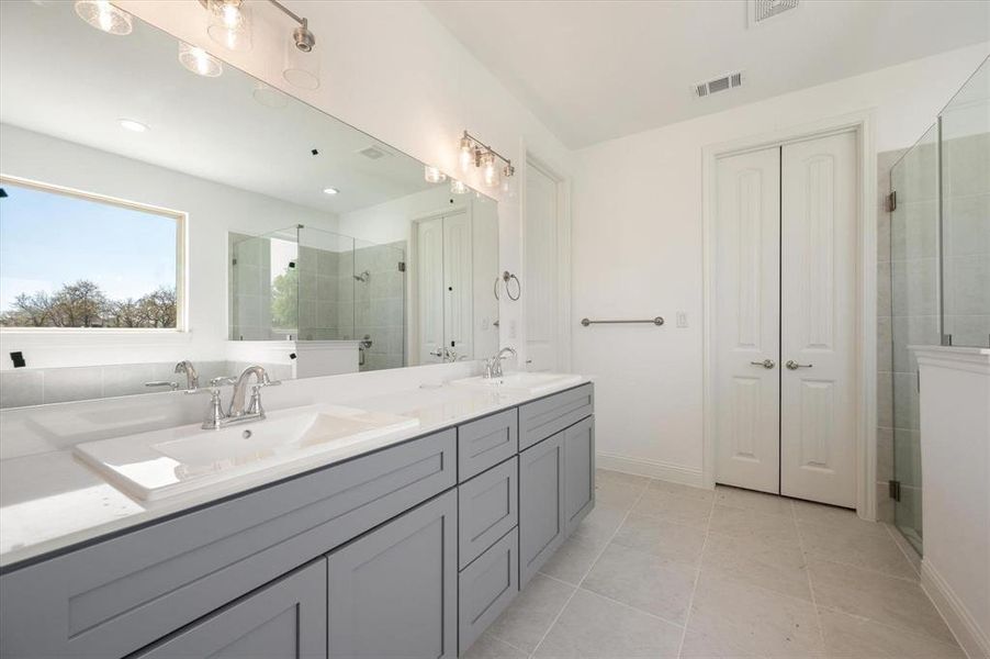 Bathroom with a shower with door, vanity, and tile patterned flooring