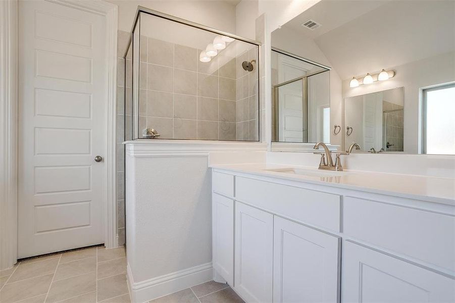 Bathroom featuring walk in shower, vanity, vaulted ceiling, and tile patterned floors