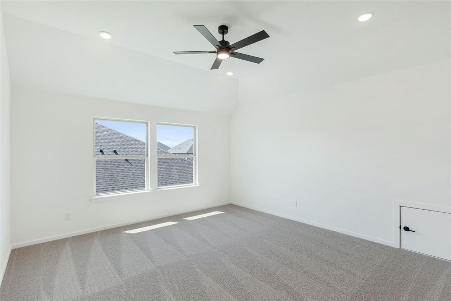 Empty bedroom with vaulted ceiling, ceiling fan, carpet flooring, and two windows
