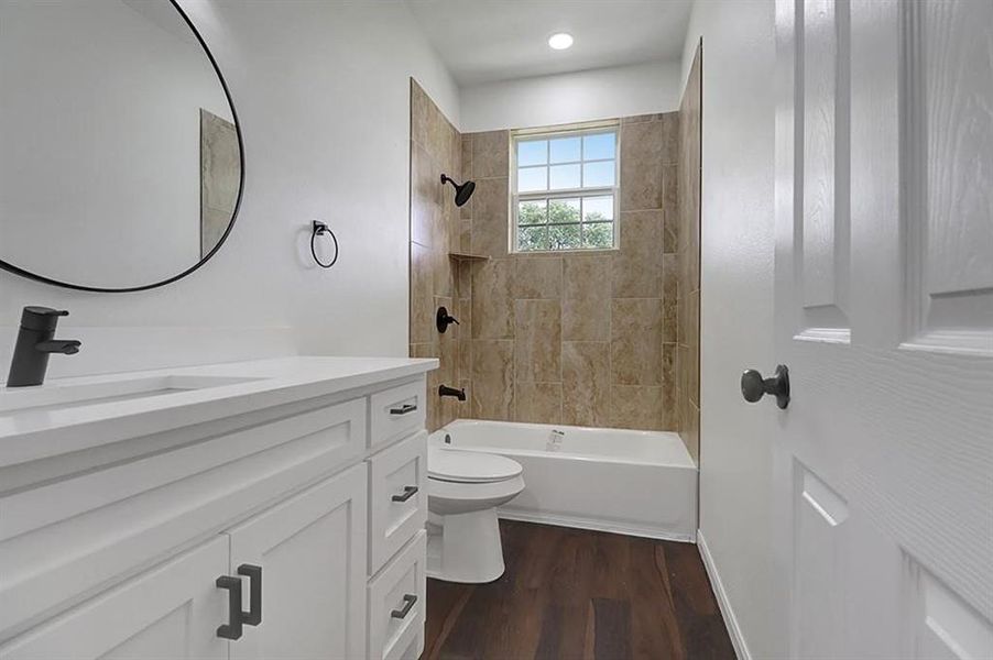 Full bathroom with tiled shower / bath, vanity, wood-type flooring, and toilet