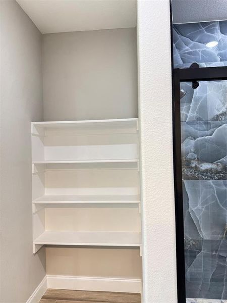 Built-in shelving unit featuring four white shelves and wood-finish flooring