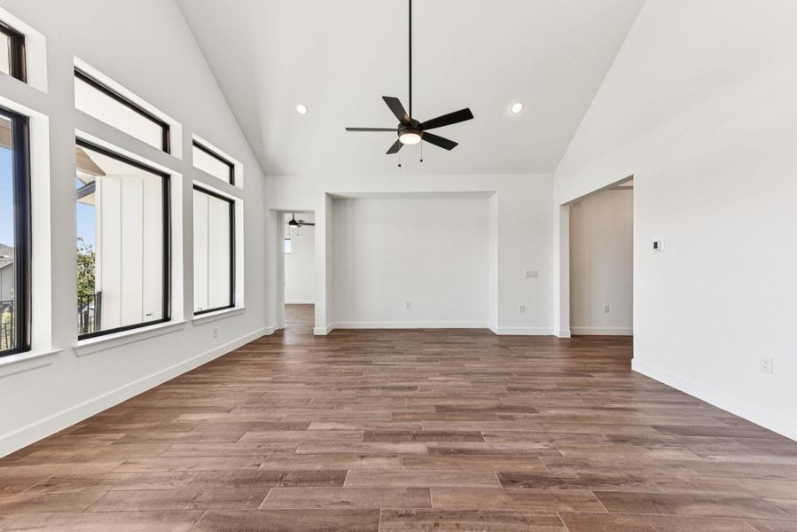 Empty room featuring high vaulted ceiling, ceiling fan, light wood-style flooring, and recessed lighting