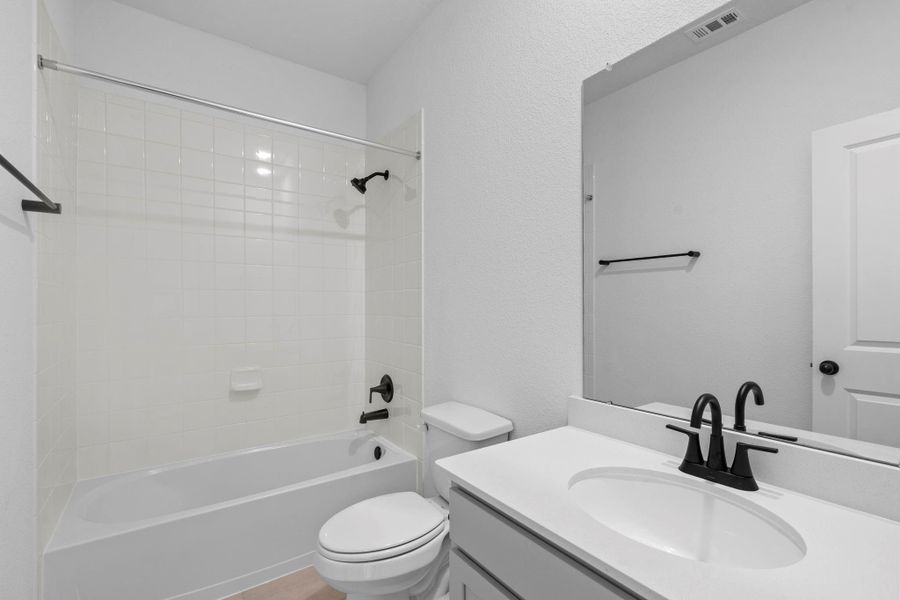 The secondary bath features tile flooring, white cabinetry and light countertops and a shower/tub combo. Perfect for accommodating any visiting family and friends.