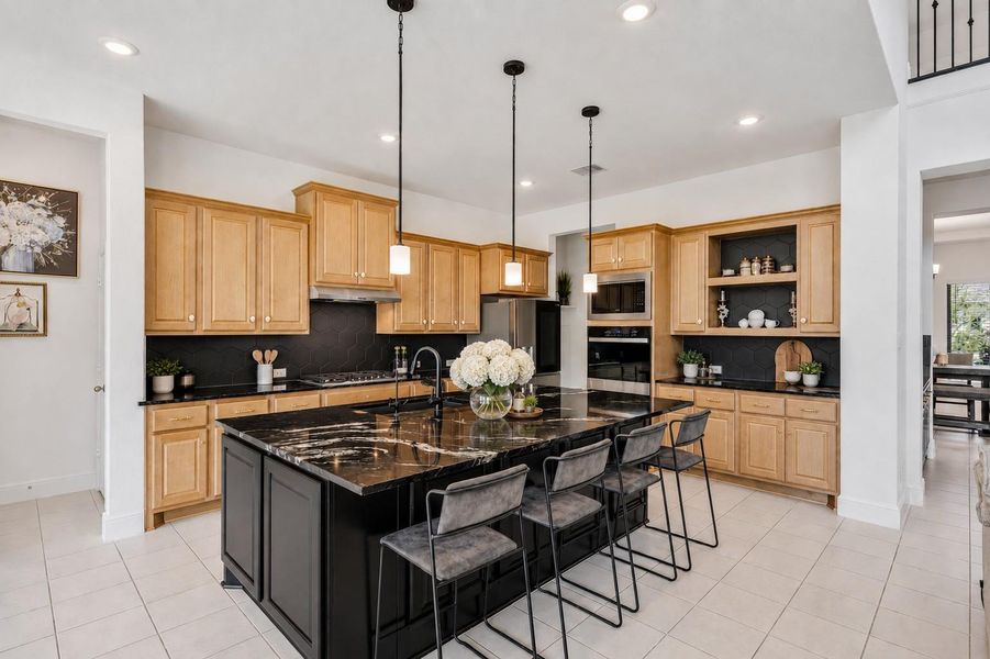 PhotGorgeous kitchen comes equipped with stainless steel appliances, beautiful natural wood cabinetry, granite countertops, a large eat-in island, 100 percent sink with drinking water and soap fixtures, a great sized pantry tucked behind the stove, and a pot filler over the stove for convenience. o