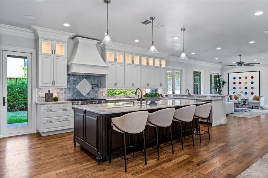 Kitchen featuring crown molding, premium range hood, a peninsula, and an island with sink Kitchen featuring crown molding, premium range hood, a peninsula, and an island with sink
