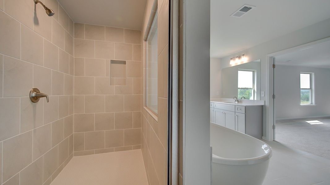 Primary bath with tile flooring, walk-in tile shower, freestanding tub in the McKinley II at Brighton in Locust Grove, GA.