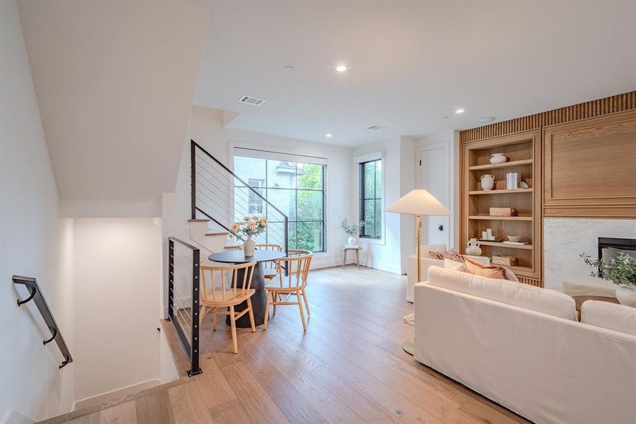 Living room featuring light wood-type flooring, built in shelves, recessed lighting, a fireplace, and stairway