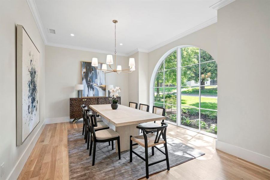 Dining room featuring wood-type flooring, crown molding, and an inviting chandelier