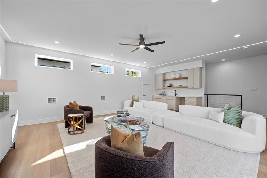 Living room with light hardwood / wood-style flooring, sink, and ceiling fan