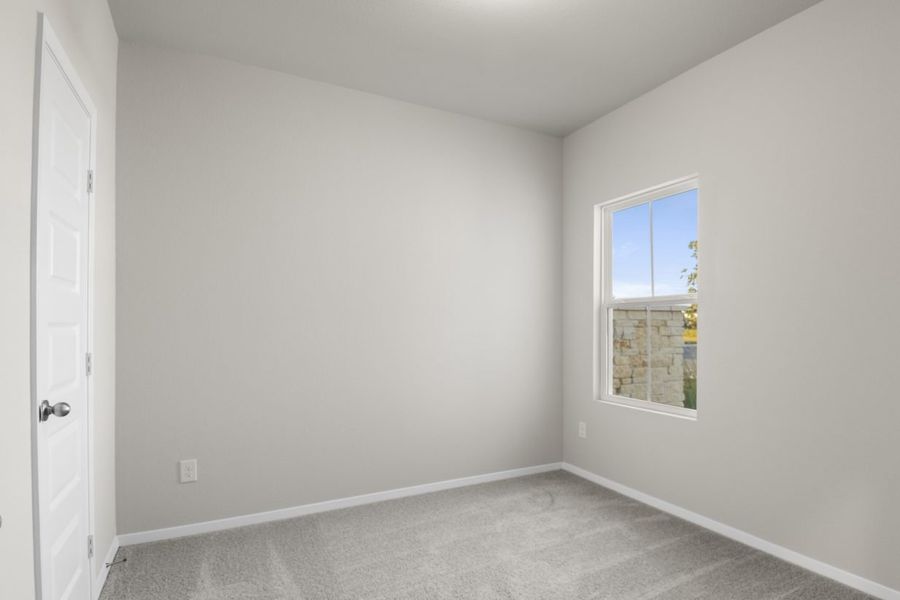 Image of a bedroom with light grey carpeting and painted walls with a window