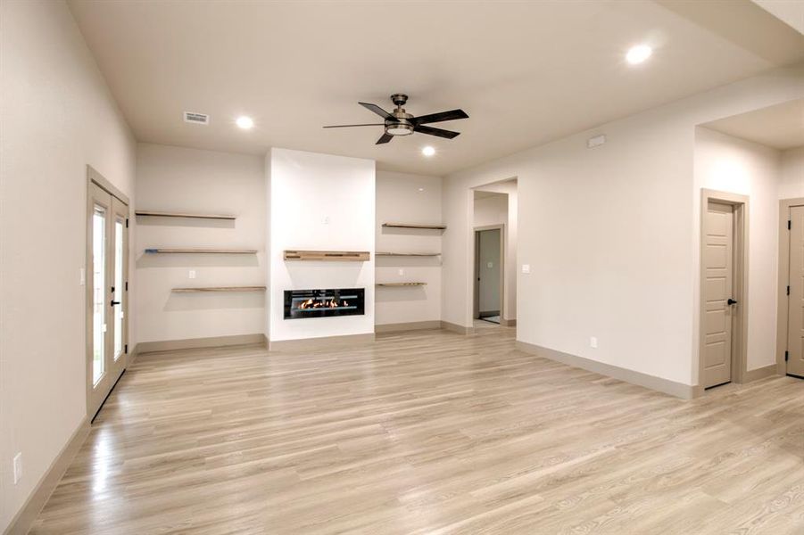Unfurnished living room featuring a glass covered fireplace, light wood-type flooring, ceiling fan, and recessed lighting