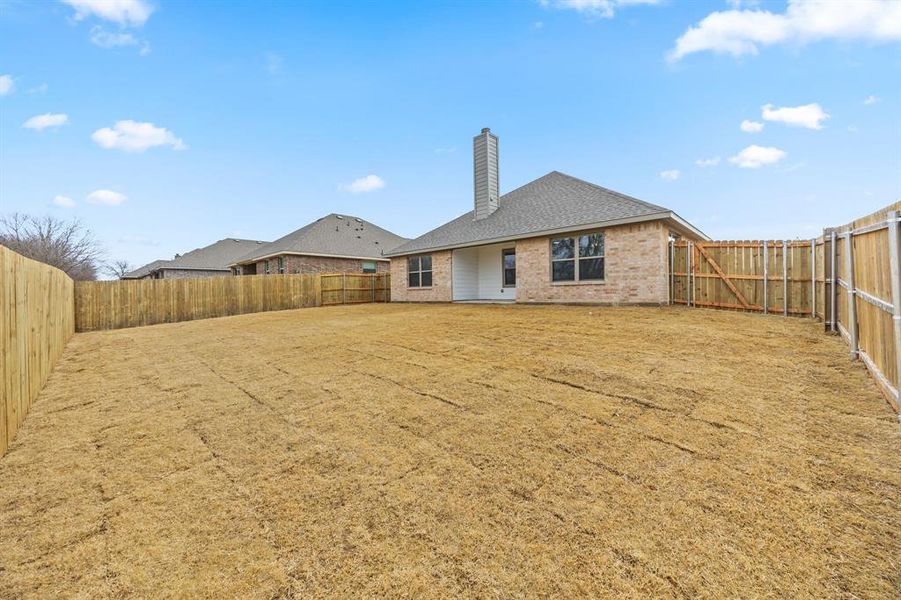 Back of property featuring a chimney, a fenced backyard, a patio area, and brick siding
