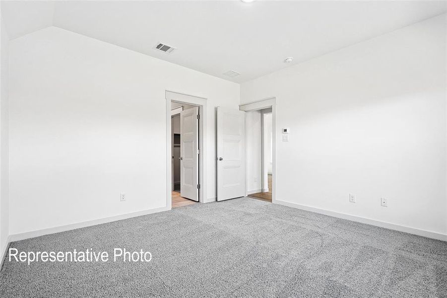 Unfurnished bedroom featuring lofted ceiling and light colored carpet