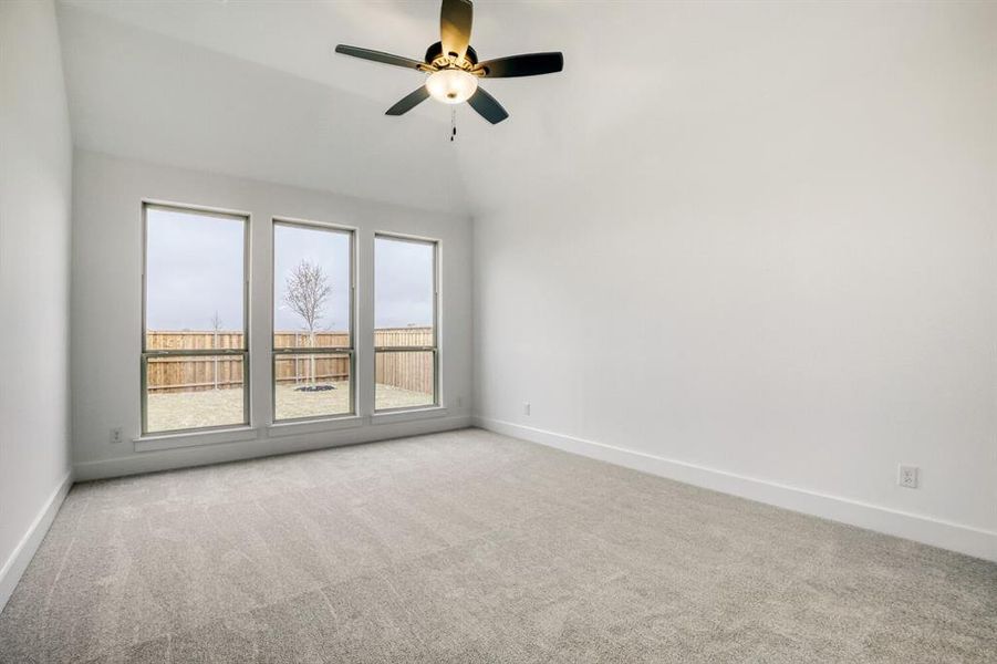 Empty room featuring carpet flooring, a ceiling fan, and vaulted ceiling