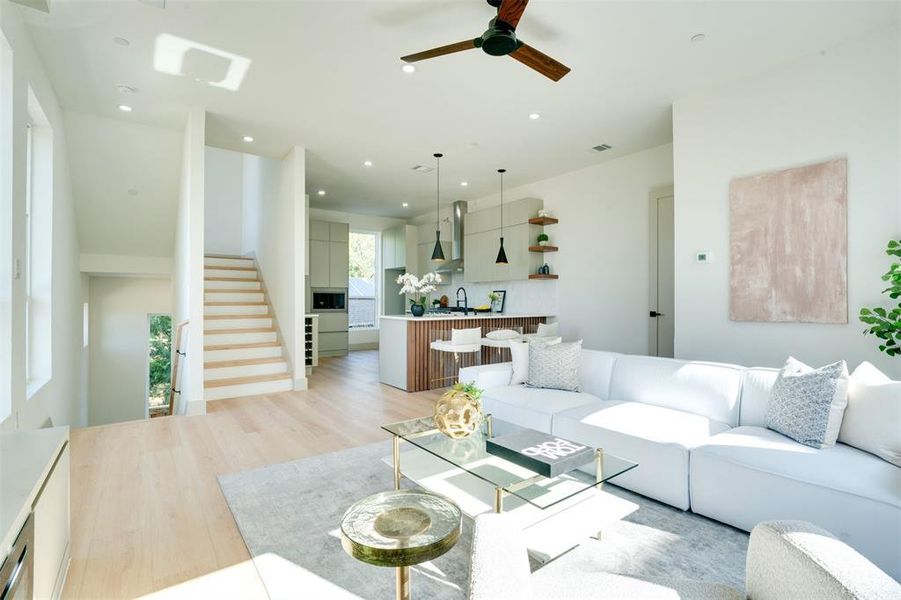 Living room with ceiling fan, sink, and light wood-type flooring