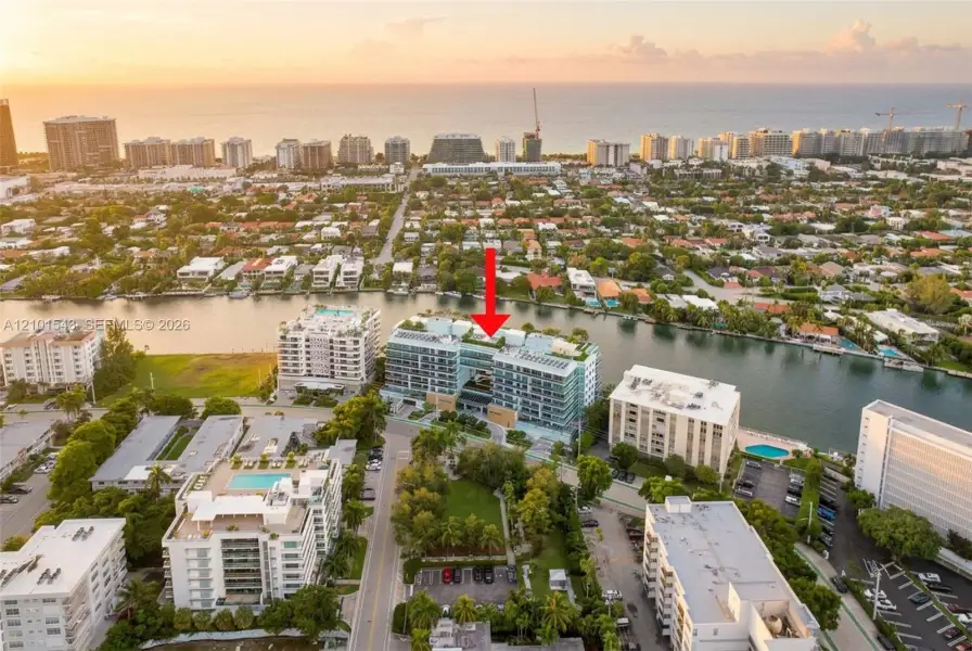 Multi-story residential building featuring floor-to-ceiling glass paneling, a rooftop pool, private balconies, and waterfront positioning along a canal