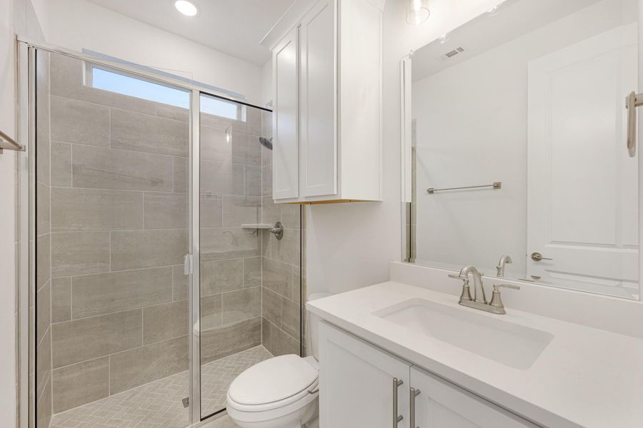 Bathroom with glass-enclosed tile shower, white vanity with quartz countertop, and large mirror Bathroom with glass-enclosed tile shower, white vanity with quartz countertop, and large mirror